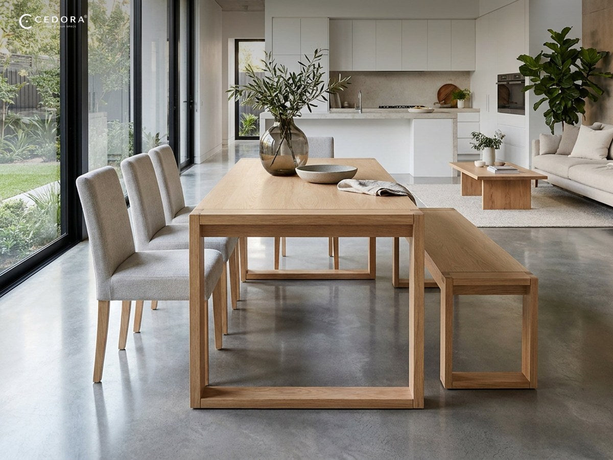 Richmond dining table in pale timber with a matching bench and upholstered chairs in an open plan room with polished concrete floors
