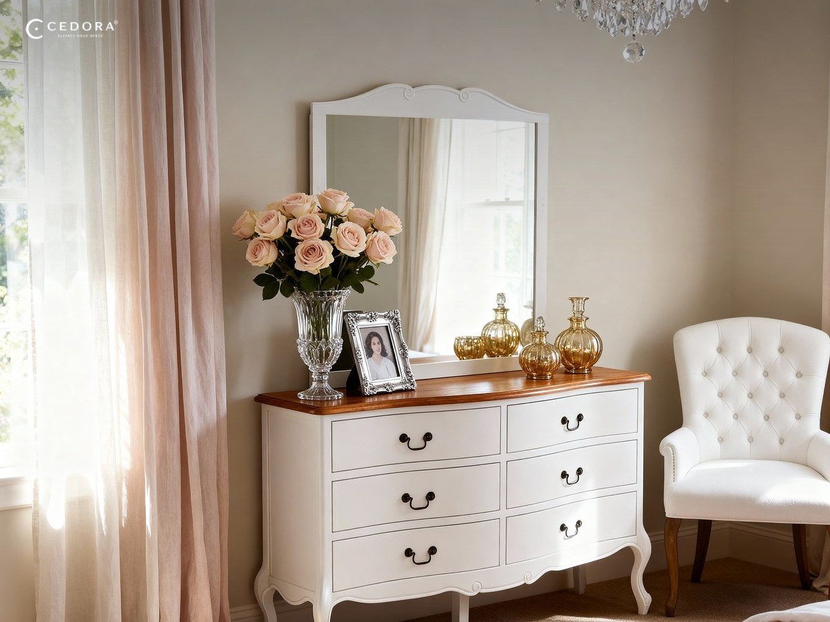 White curved six drawer chest with a timber top styled with roses and glassware beside a window
