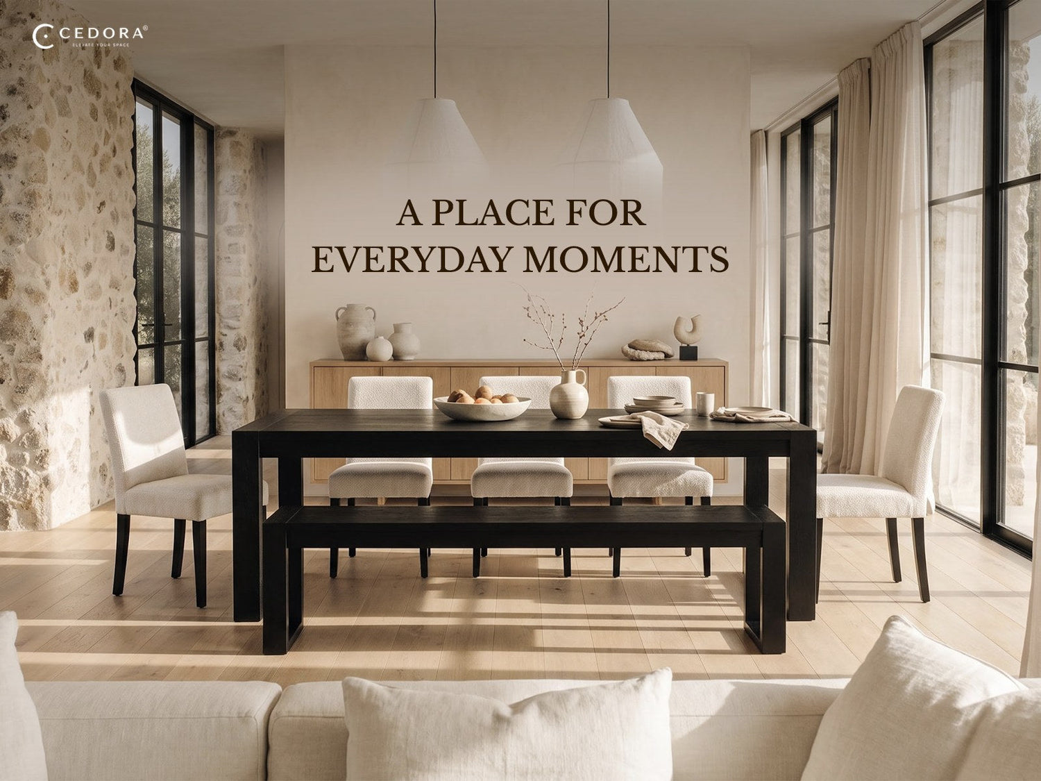 A place for everyday moments - a black dining table with a matching bench and white upholstered chairs in a light dining room with a stone wall