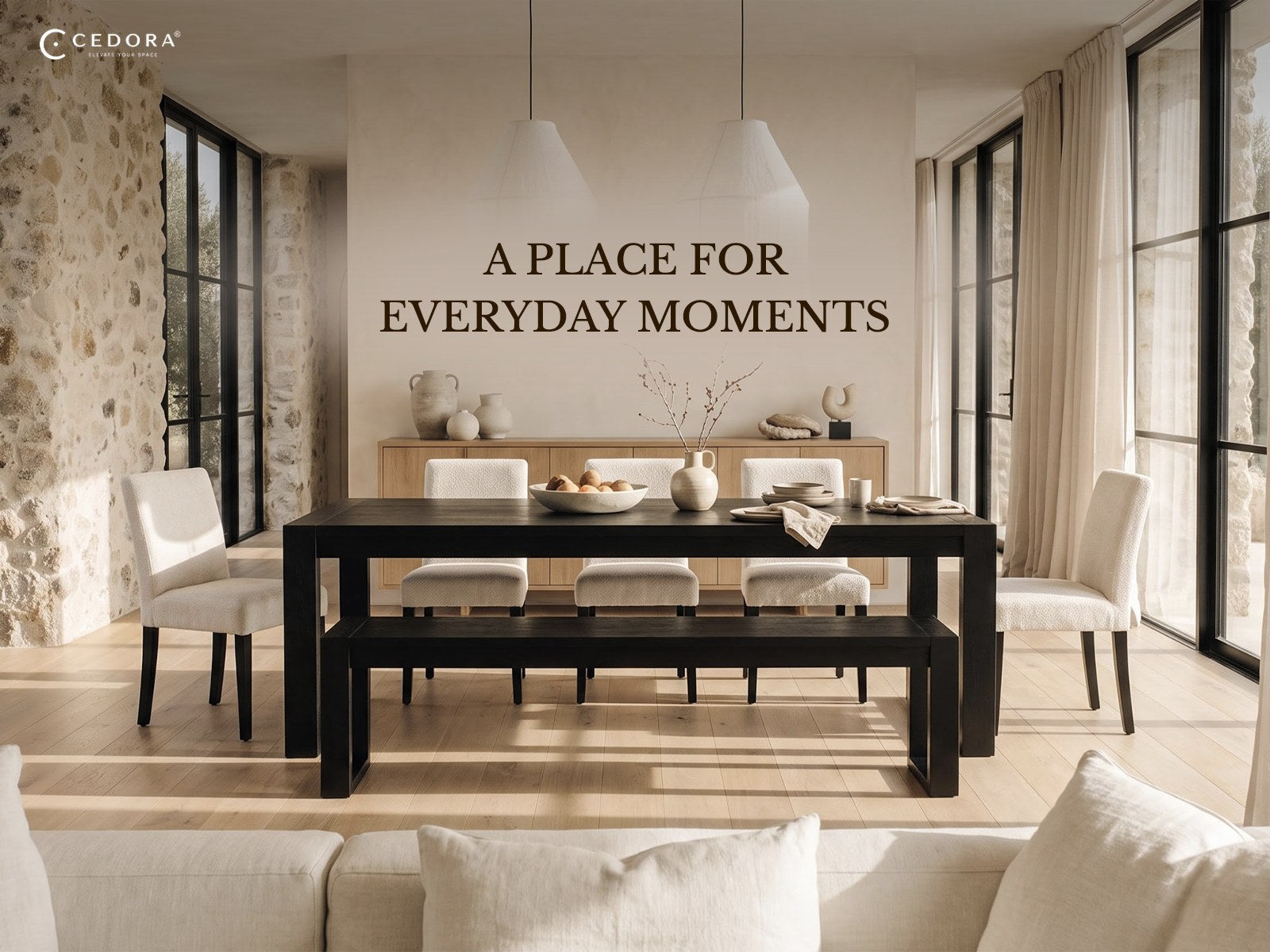 A place for everyday moments - a black dining table with a matching bench and white upholstered chairs in a light dining room with a stone wall