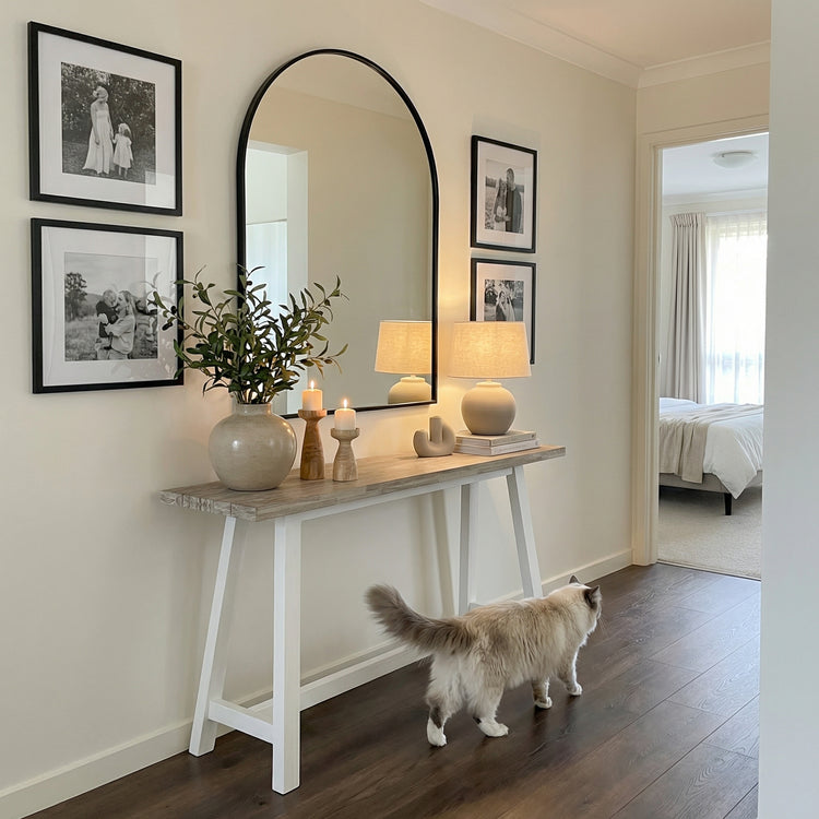 Cat walking past a console table with decor items in a bedroom setting

