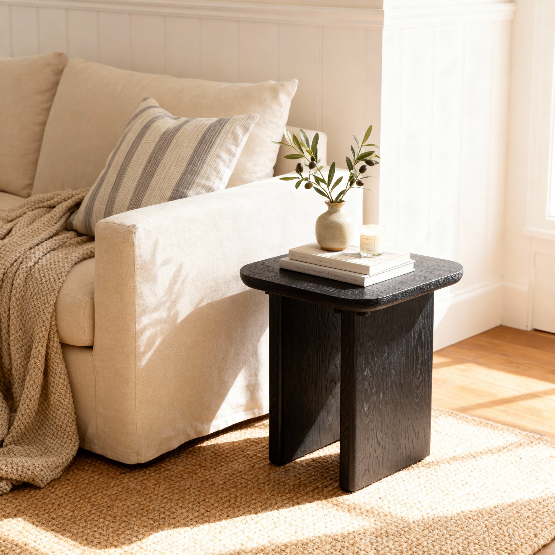 Beige sofa with a black side table and decorative items in a living room setting.

