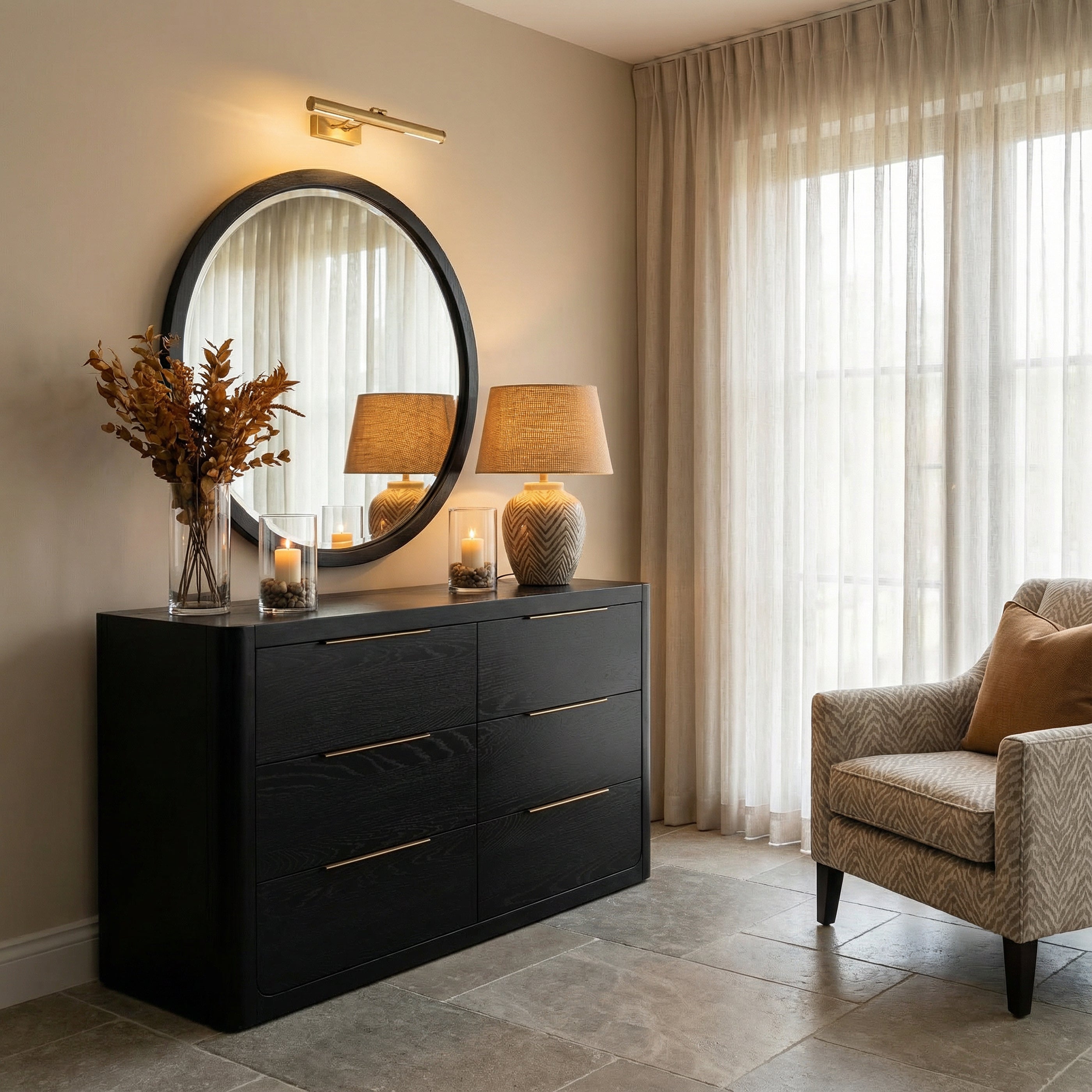 Modern interior with a black dresser, round mirror, and armchair.

