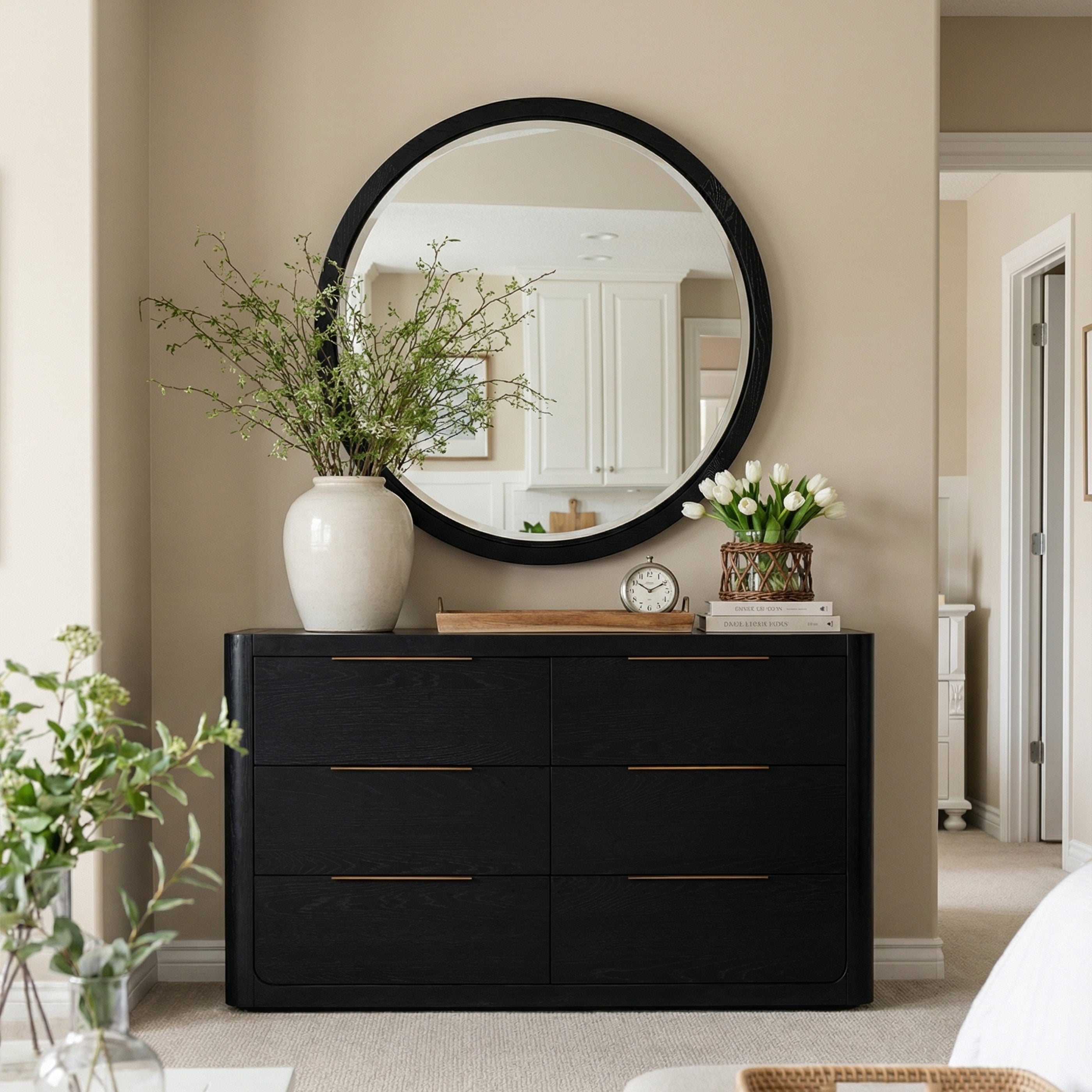 Black dresser with decorative items including a round mirror, vase, and clock in a room setting.

