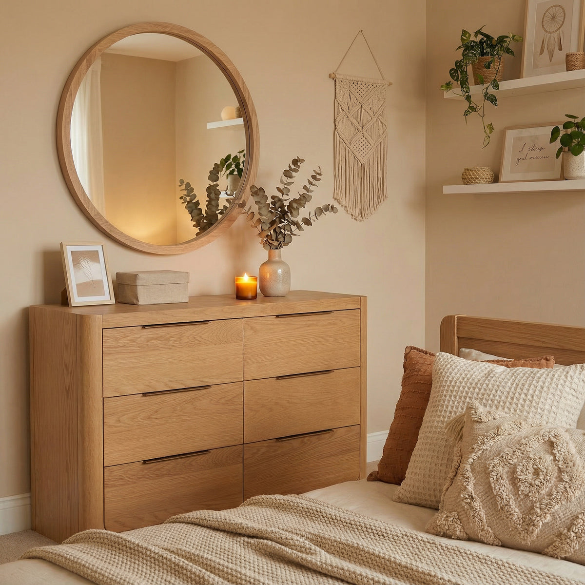 Wooden dresser in a bedroom with a round mirror, candles, and decorative items.

