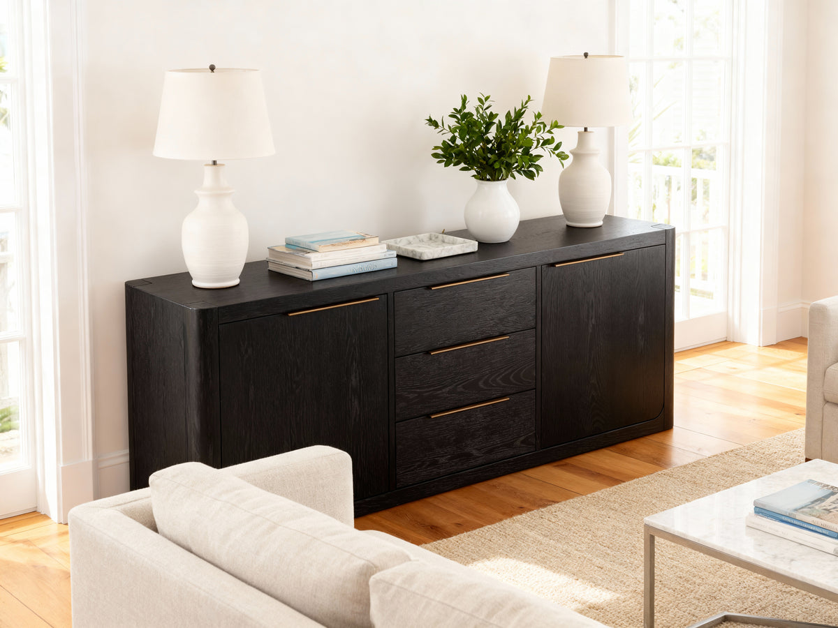 Black dresser with gold handles in a living room setting

