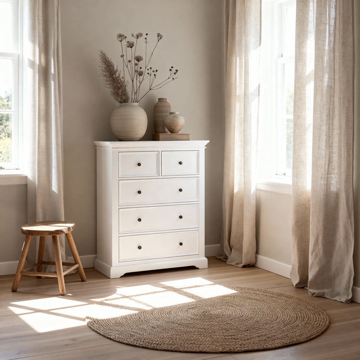 London Pine 5 Drawer Tallboy in a corner between two curtained windows, topped with dried blooms beside a timber stool