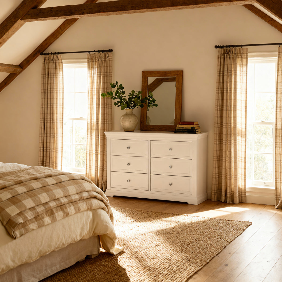 Bedroom with white dresser, plaid blanket, and large windows with curtains.

