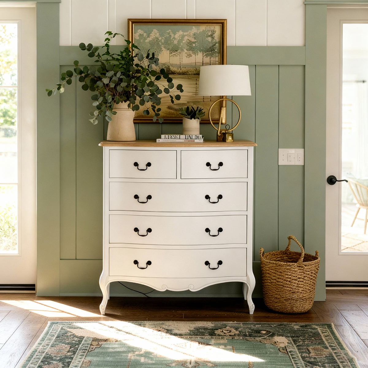 Newcastle Acacia 5 Drawer Tallboy against sage green panelling, topped with eucalyptus and a lamp beside a woven basket