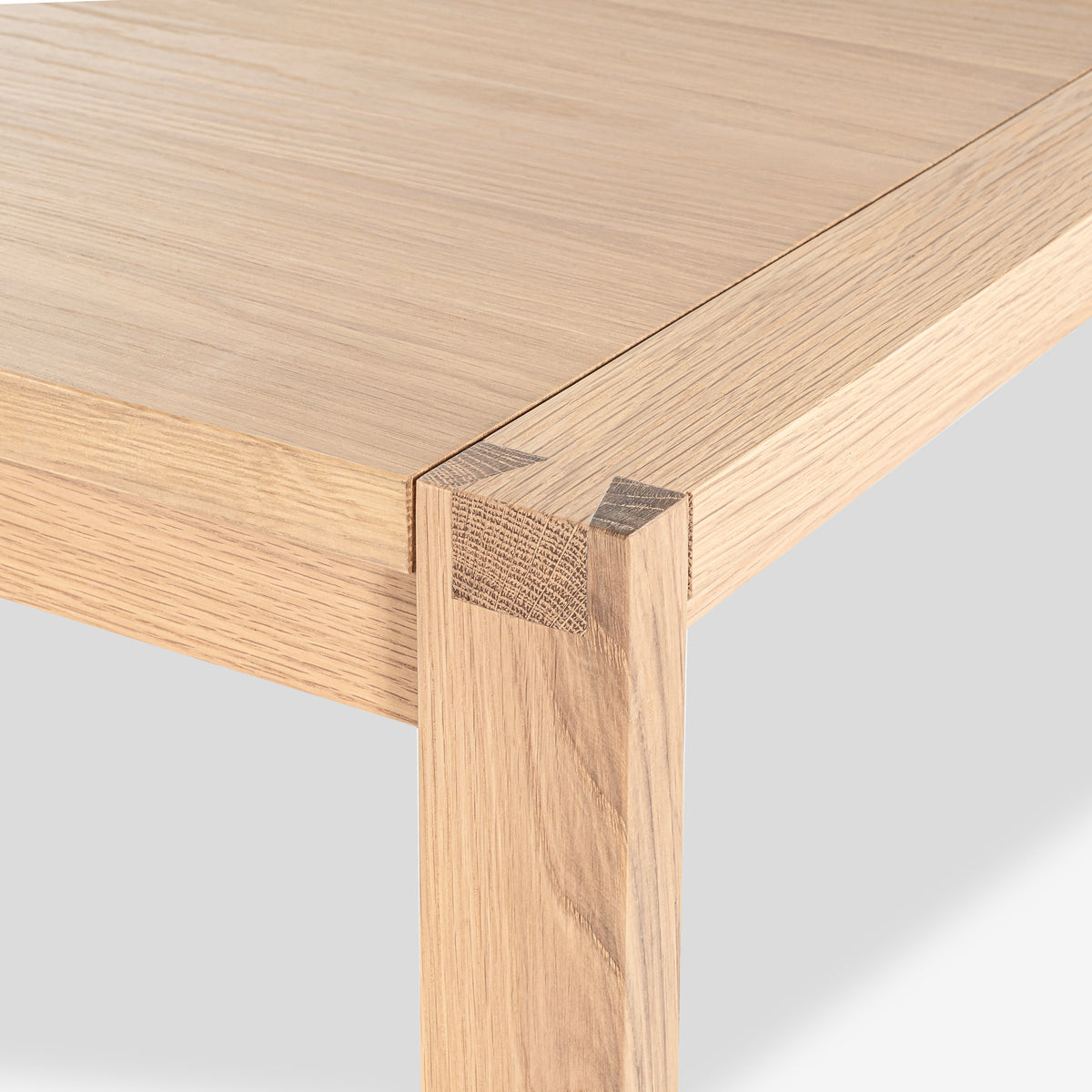 Close-up of a wooden table corner with a light finish on a white background

